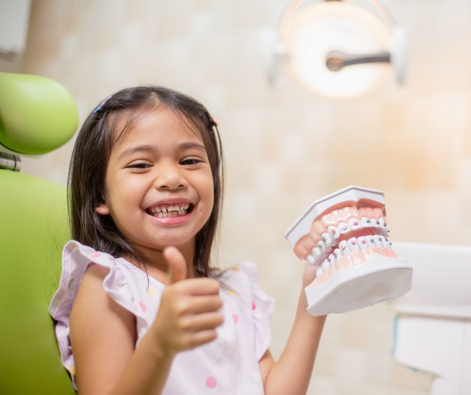 Girl holding teeth. pediatric orthodontics